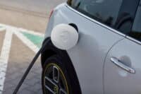 Charging port of a Mini Cooper SE Electric connected to a charger, highlighting the eco-friendly and urban design of the vehicle