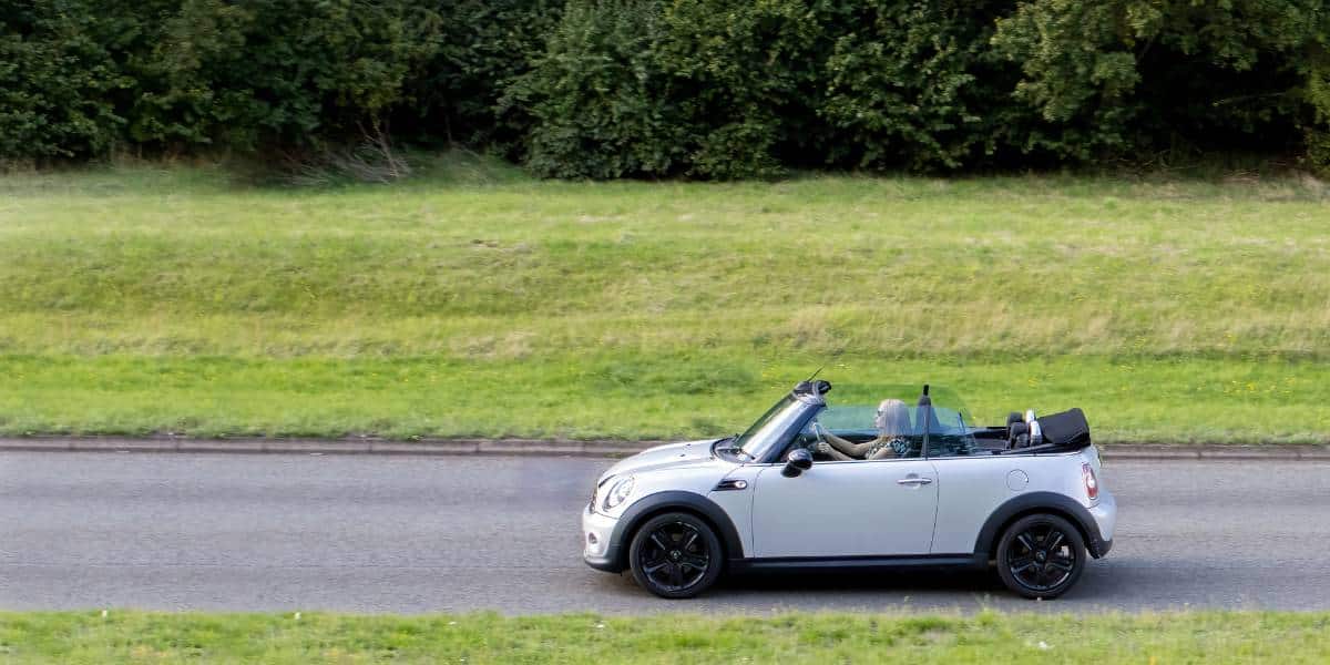 Mini Cooper Price is budget friendly; woman is driving off happily after paying a fair price.