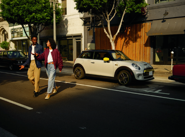 A couple walking away from their parked Mini Cooper SE