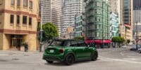 Green mini cooper parked in front of buildings.