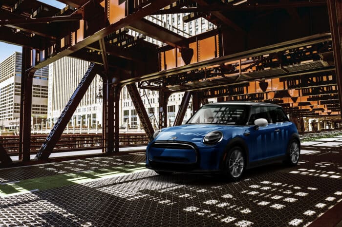 Blue Mini Cooper driving under a bridge.