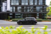 Dynamic side view of a black Mini Cooper F56 speeding through an urban setting, showcasing its sleek design and sporty appeal