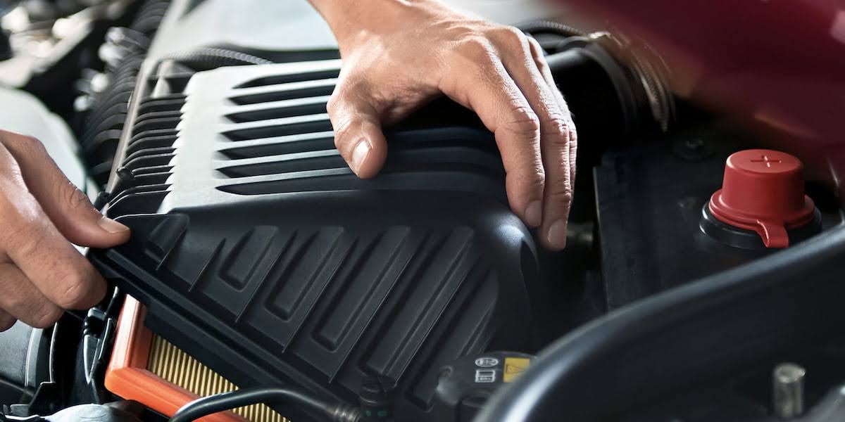 A close-up of a mechanic inspecting the engine of a Mini Cooper, highlighting maintenance practices that influence the Mini Cooper reliability rating.