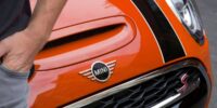 Close-up of the front of an orange Mini Cooper S with iconic grille and logo, symbolizing style and coverage under the Mini Cooper warranty.