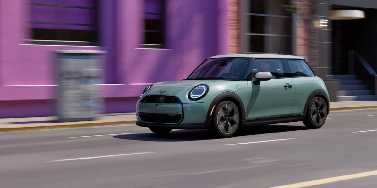 Mint green MINI Cooper driving on city street with purple buildings - available through MINI Financial Services financing programs for qualified buyers