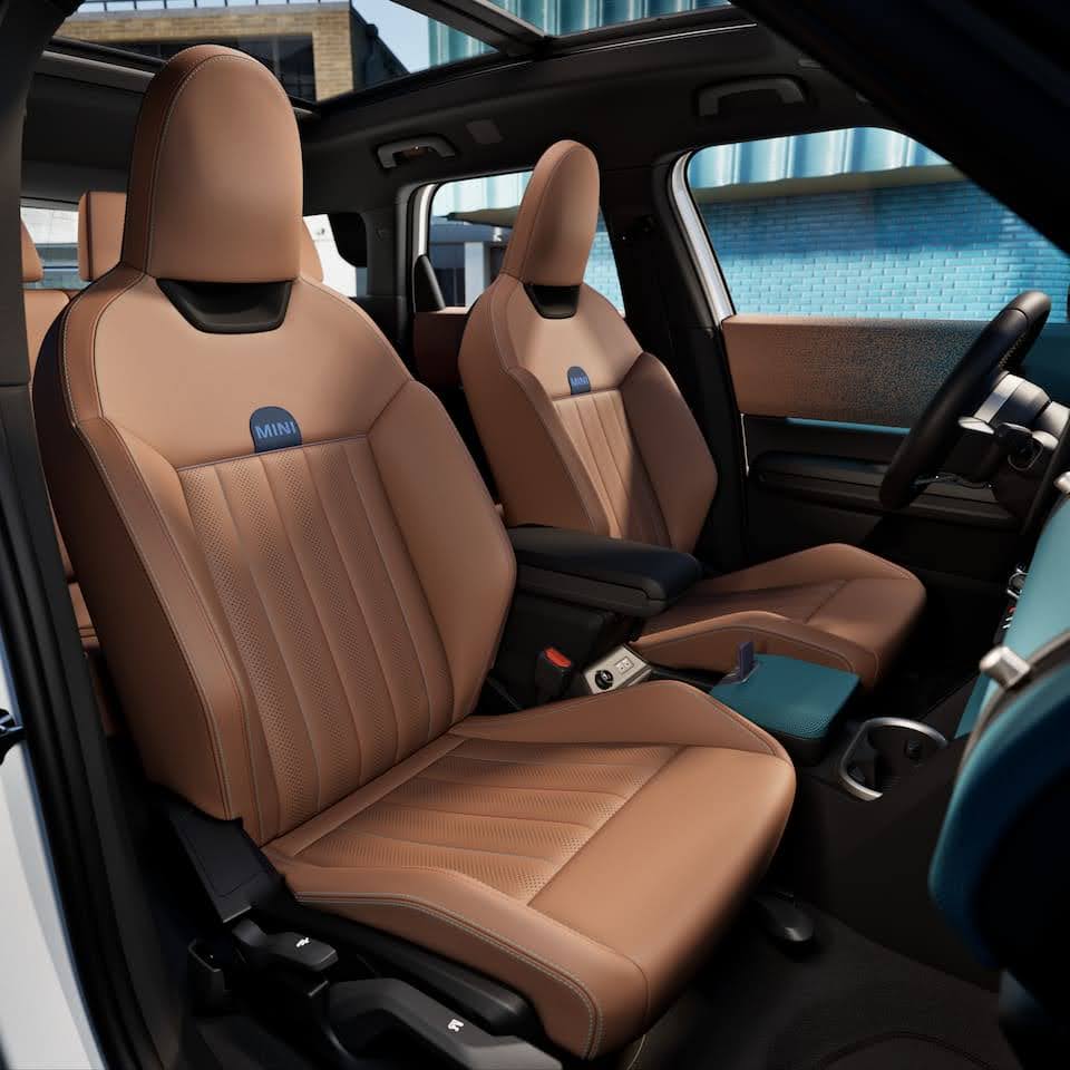 MINI Cooper SE electric hatchback driving on city street showcasing its distinctive styling and compact design
