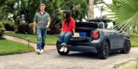 Couple with MINI Cooper convertible discussing mpg meaning and fuel efficiency while enjoying outdoor lifestyle