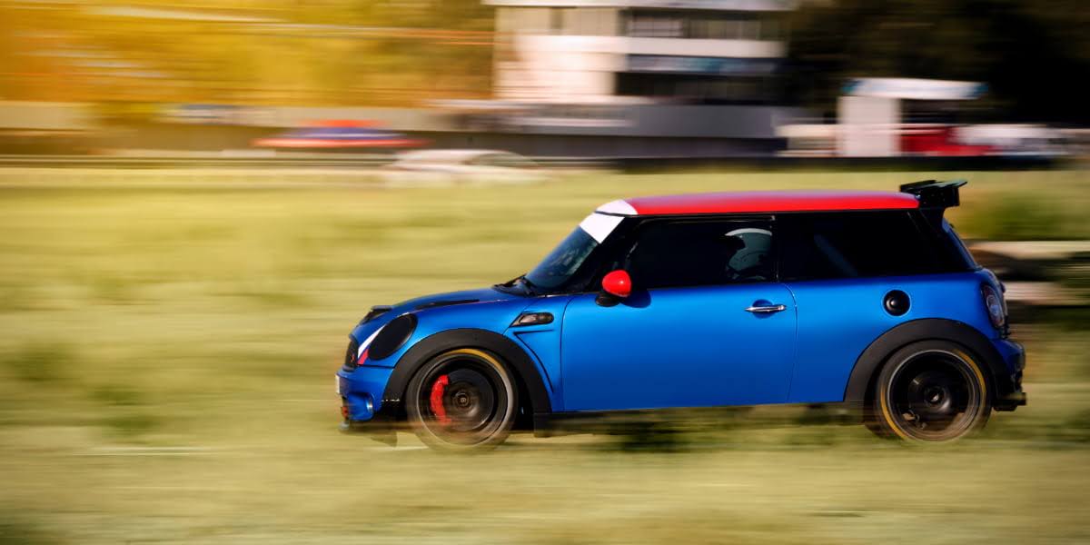 Blue Mini Cooper GP with red roof racing on track, showcasing high-performance design and speed of the mini cooper gp.