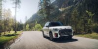 White 2025 mini cooper countryman driving through a scenic mountain road showcasing bold new design and SUV capability.