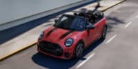 Red mini convertible driving with top down on sunny road showcasing open-air design and fun driving experience.