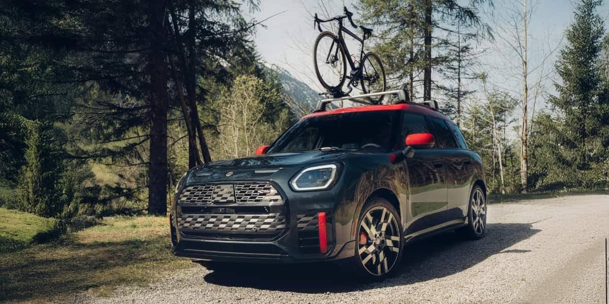 Mini Cooper with roof-mounted bike rack on a scenic road, representing Mini Cooper mods focused on performance and lifestyle upgrades.