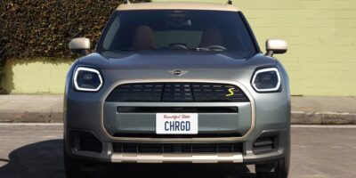 Front view of a gray electric Mini parked on a city street showing the grille and headlights of the 2026 Mini Cooper EV