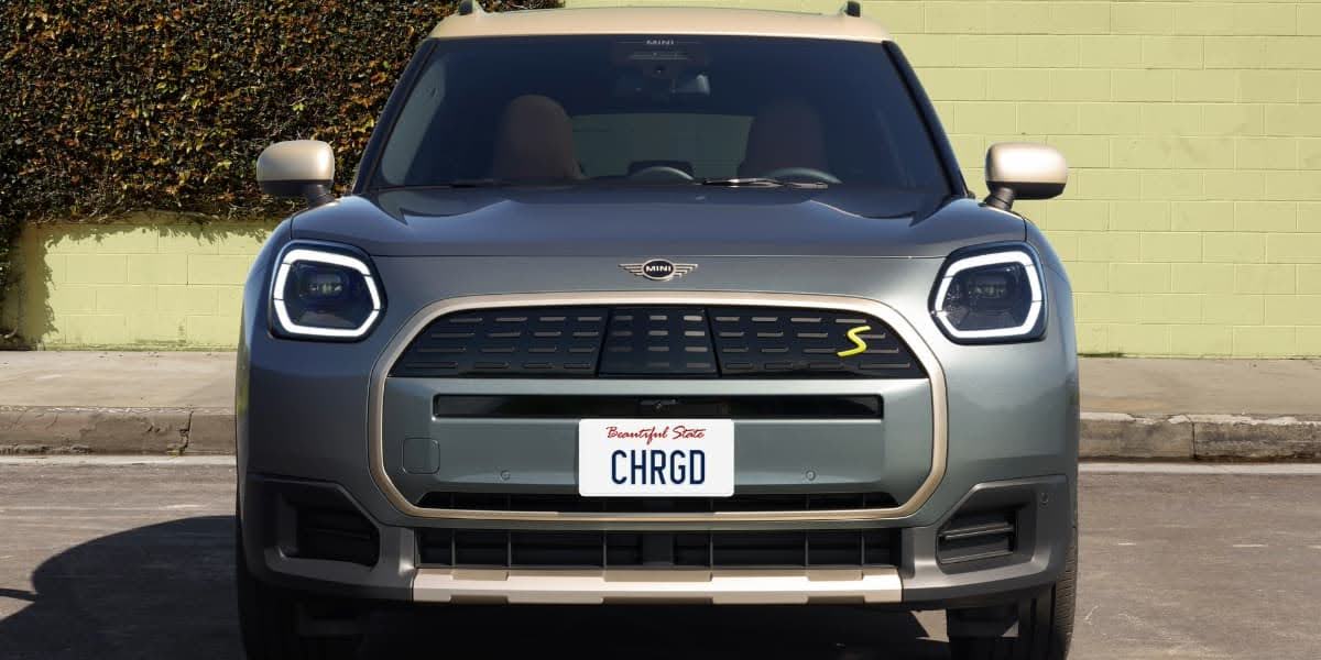 Front view of a gray electric Mini parked on a city street showing the grille and headlights of the 2026 Mini Cooper EV