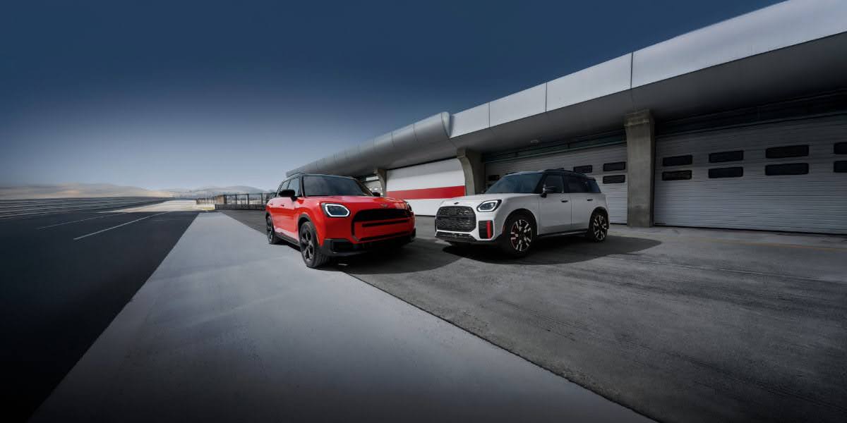Two MINI vehicles parked outside a modern garage showcasing Mini Cooper trim levels with different exterior styling and wheel designs