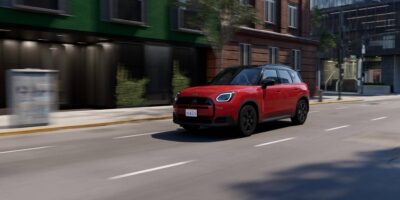 Red 2026 MINI Cooper driving through a city street illustrating Mini Cooper maintenance for urban daily use