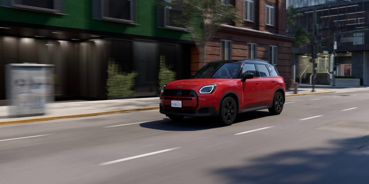 Red 2026 MINI Cooper driving through a city street illustrating Mini Cooper maintenance for urban daily use